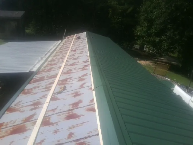 Old rusted panels beside newly installed green metal roofing — Wind Damage Roof Repair by Roofing Brothers in Hockley