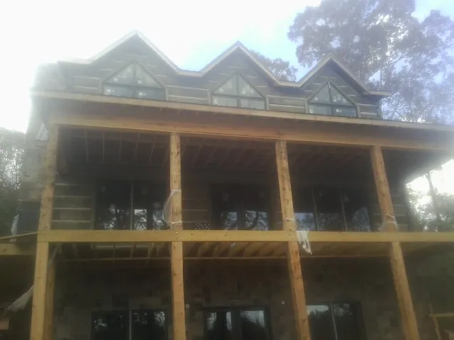 Dormers and porch framing on a large log home under construction — Roof Coating work by our crew in Hockley