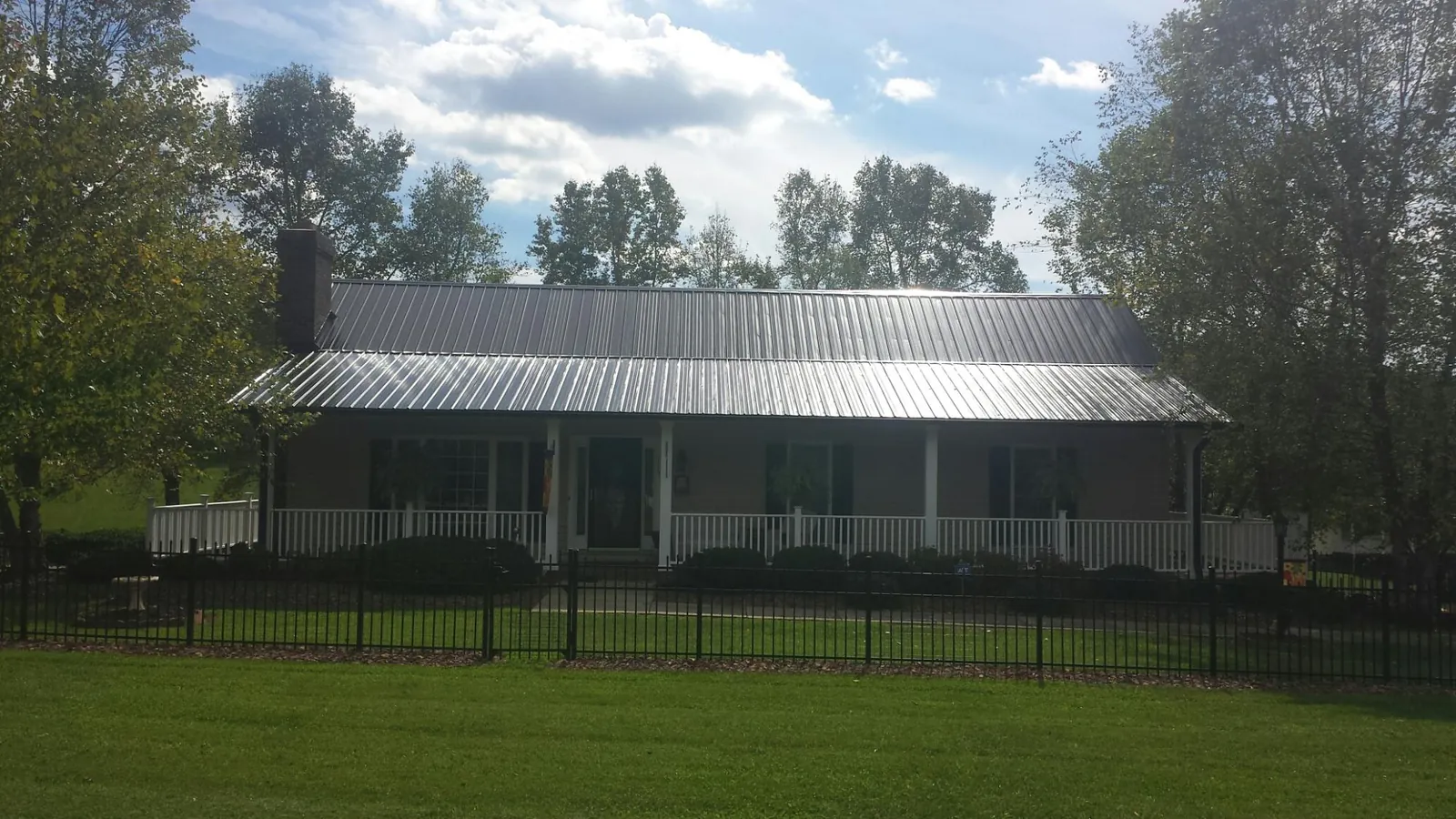 Gray metal roof on a brick ranch with a full width front porch — Gutter Guard Installation work by our crew in Hockley
