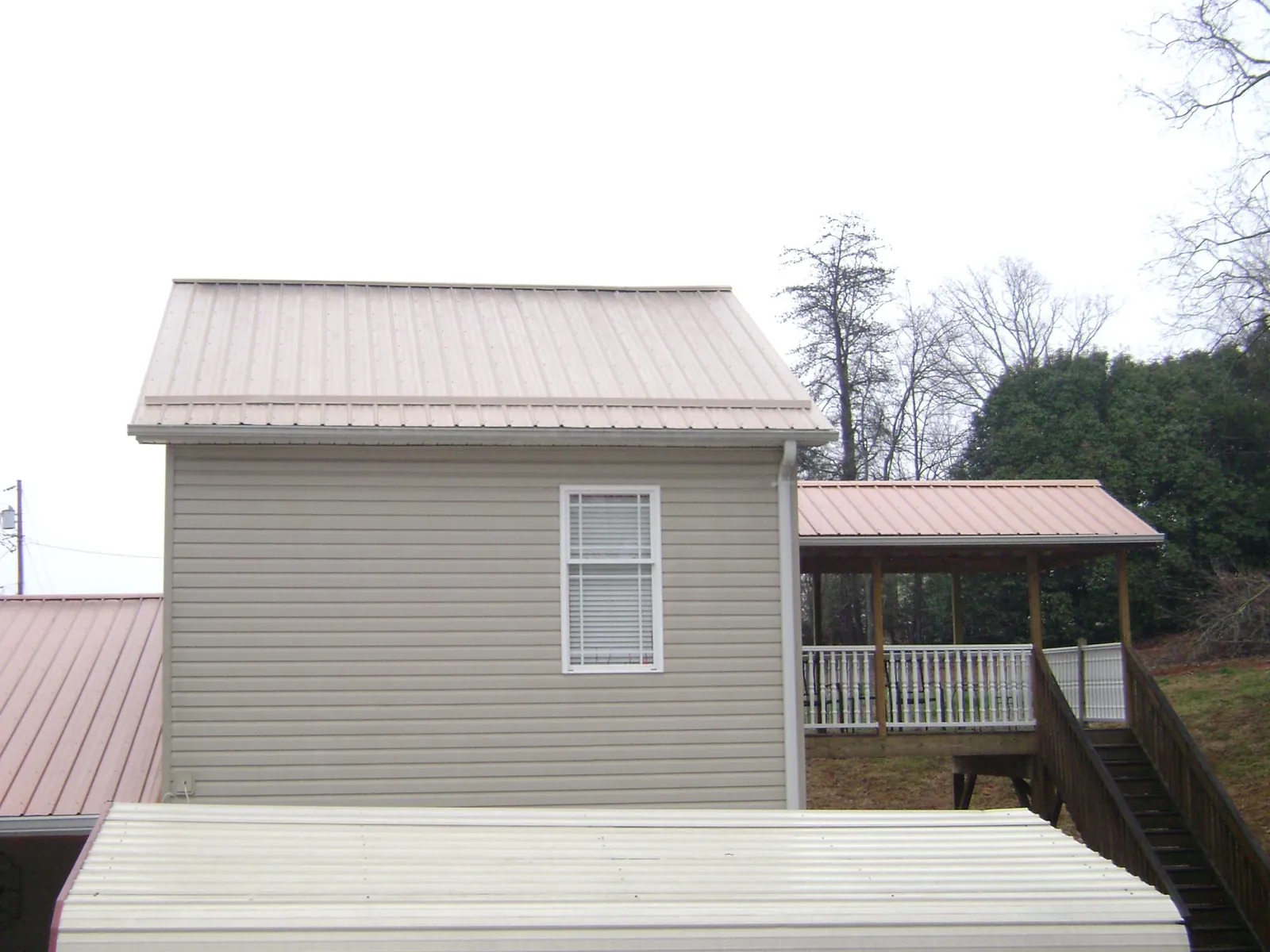 Tan metal roofs on a two story addition and attached porch, from a Roof Replacement job in Hockley