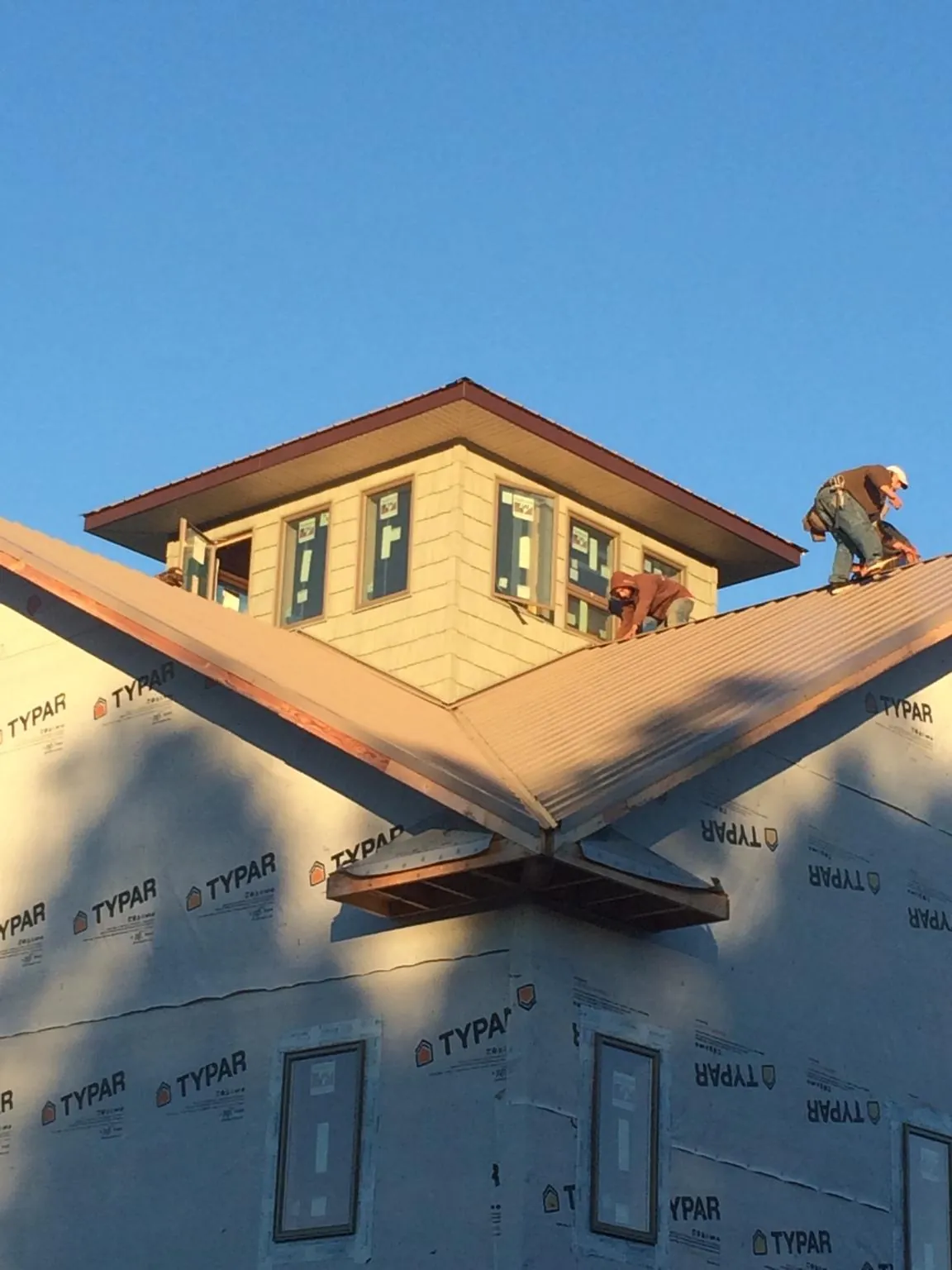 Roofers working around a rooftop cupola on a new metal roof at sunset — Roof Waterproofing in Hockley by Roofing Brothers